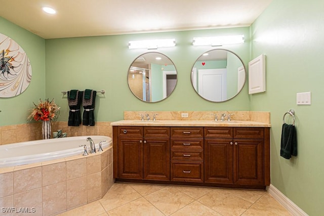 bathroom featuring tile patterned flooring, a relaxing tiled tub, and vanity