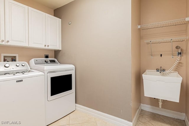 clothes washing area featuring cabinets, light tile patterned floors, sink, and washing machine and clothes dryer