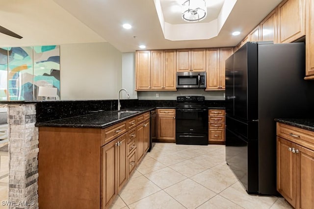 kitchen with black appliances, sink, dark stone countertops, light tile patterned floors, and a tray ceiling