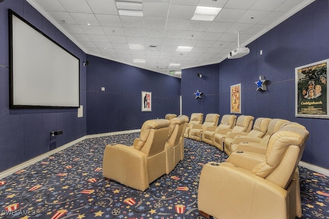 carpeted home theater with a paneled ceiling and crown molding