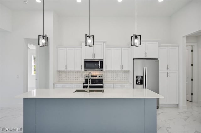 kitchen featuring a center island with sink, decorative light fixtures, white cabinetry, and appliances with stainless steel finishes