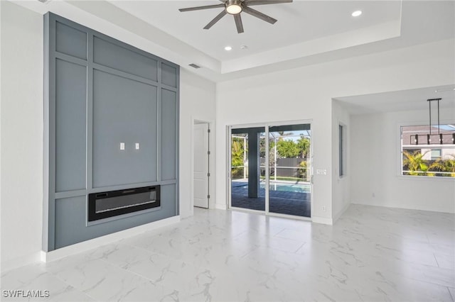 unfurnished living room featuring a raised ceiling and ceiling fan