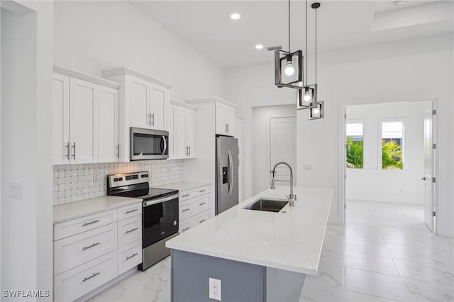 kitchen featuring sink, stainless steel appliances, decorative light fixtures, a kitchen island with sink, and white cabinets