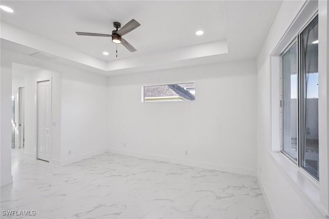 empty room featuring a tray ceiling and ceiling fan