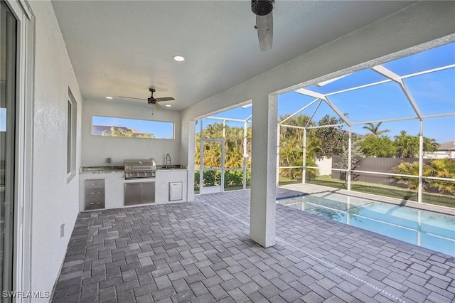 view of patio with an outdoor kitchen, a lanai, sink, and grilling area