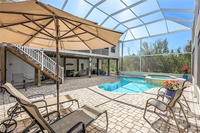 view of swimming pool with a patio area, a pool with connected hot tub, stairs, and glass enclosure