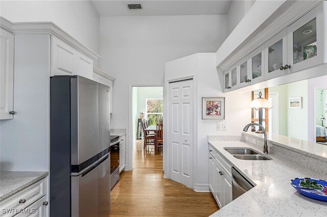 kitchen featuring a sink, visible vents, white cabinetry, appliances with stainless steel finishes, and glass insert cabinets