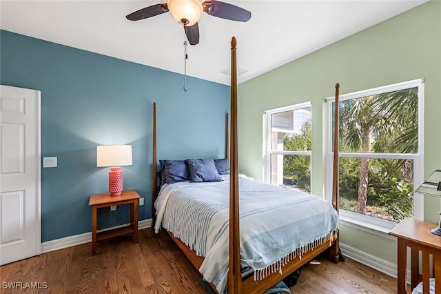 bedroom with multiple windows, baseboards, and wood finished floors