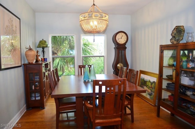 dining area with baseboards, wood finished floors, and a notable chandelier