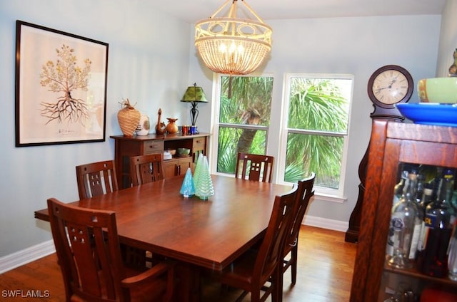 dining space featuring a chandelier, a fireplace, baseboards, and wood finished floors