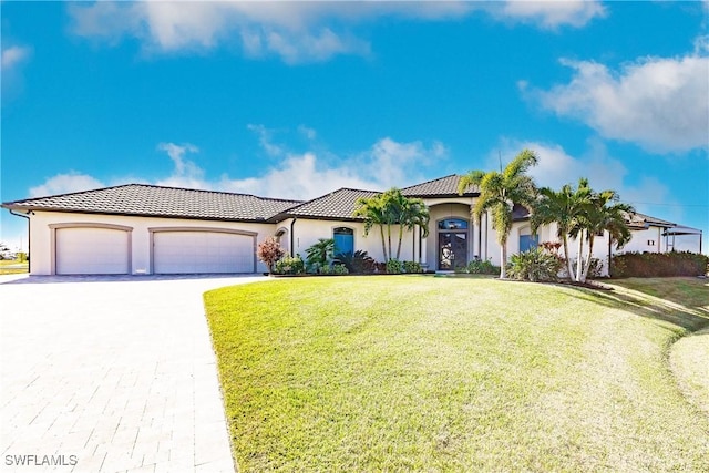 mediterranean / spanish-style house with a garage and a front lawn