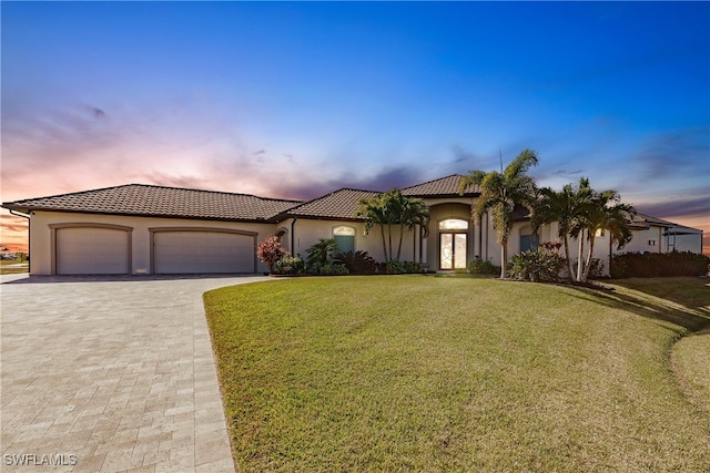 mediterranean / spanish house with a garage and a lawn