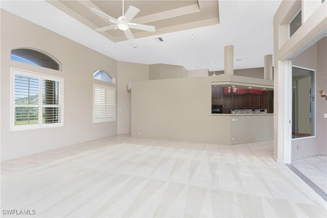 unfurnished living room with a high ceiling, light carpet, and ceiling fan