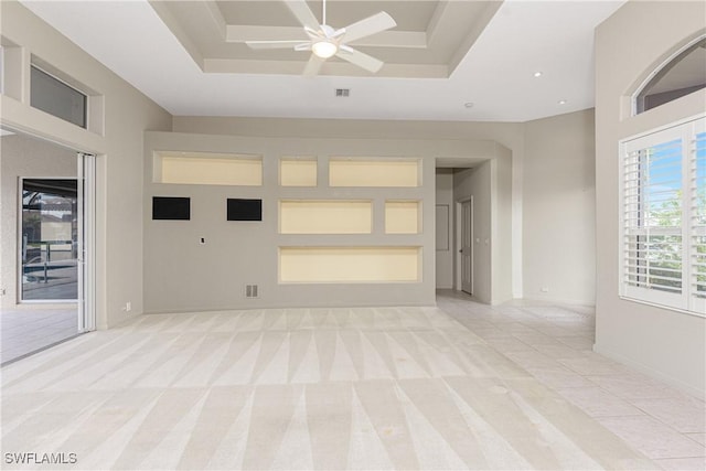 carpeted empty room with a raised ceiling and ceiling fan