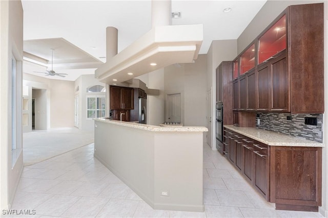 kitchen featuring light tile patterned floors, ceiling fan, stainless steel fridge, black double oven, and backsplash