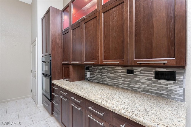 kitchen featuring decorative backsplash, light tile patterned floors, and light stone counters