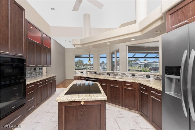 kitchen with a center island, stainless steel fridge with ice dispenser, light tile patterned floors, decorative backsplash, and sink