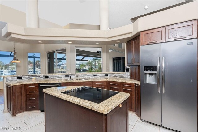 kitchen featuring a kitchen island, a high ceiling, black appliances, and sink