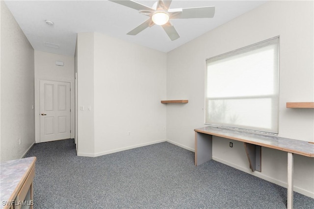 unfurnished office featuring ceiling fan and dark colored carpet