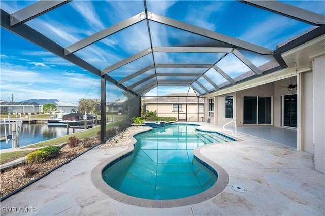 view of swimming pool with a patio, a lanai, ceiling fan, and a water view