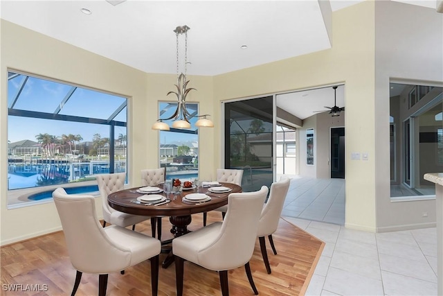 dining space featuring ceiling fan with notable chandelier, light tile patterned flooring, and plenty of natural light