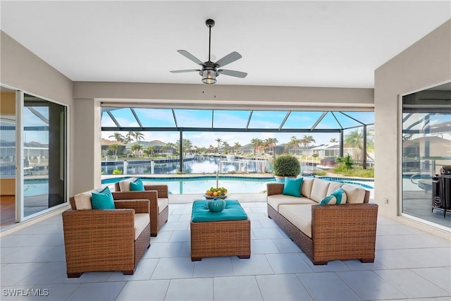 sunroom featuring ceiling fan and a water view