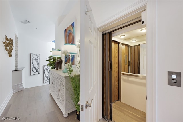 corridor with light hardwood / wood-style floors and elevator