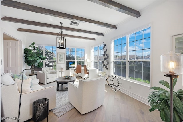 living room with beamed ceiling, light hardwood / wood-style floors, and a chandelier