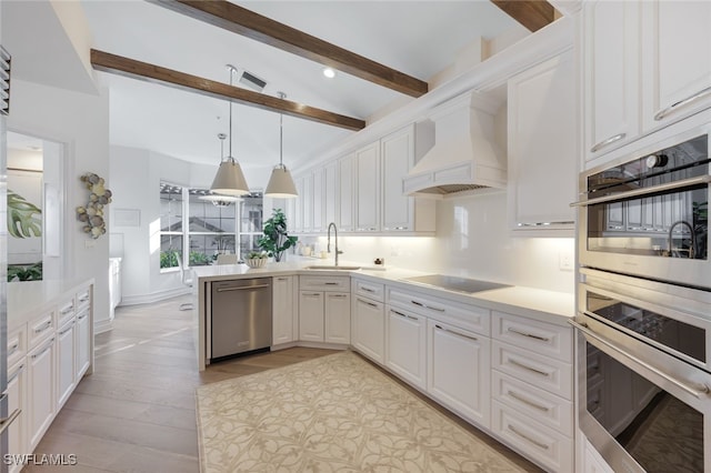 kitchen featuring appliances with stainless steel finishes, light wood-type flooring, custom exhaust hood, white cabinetry, and hanging light fixtures