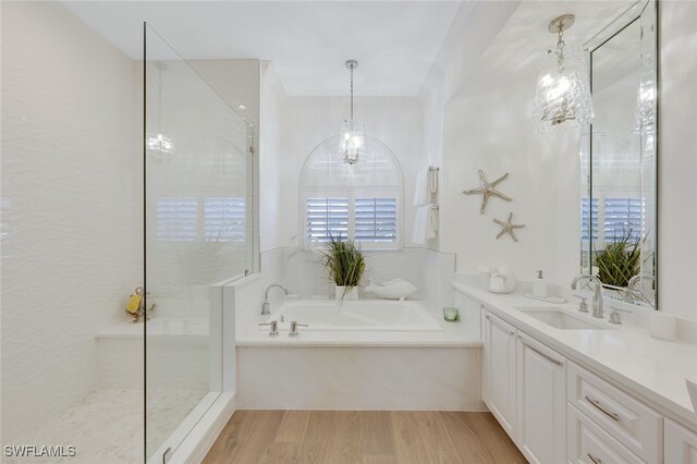 bathroom featuring a notable chandelier, vanity, wood-type flooring, and independent shower and bath