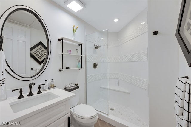 bathroom with a tile shower, vanity, and toilet