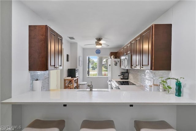 kitchen featuring white appliances, a breakfast bar area, and backsplash