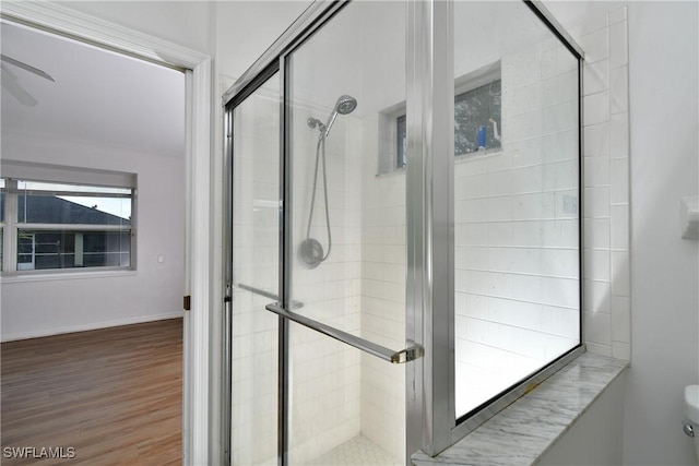 bathroom with ceiling fan, a shower with door, and hardwood / wood-style flooring