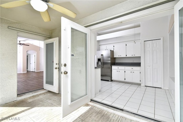 kitchen with white cabinets, stainless steel fridge, light tile patterned floors, and french doors