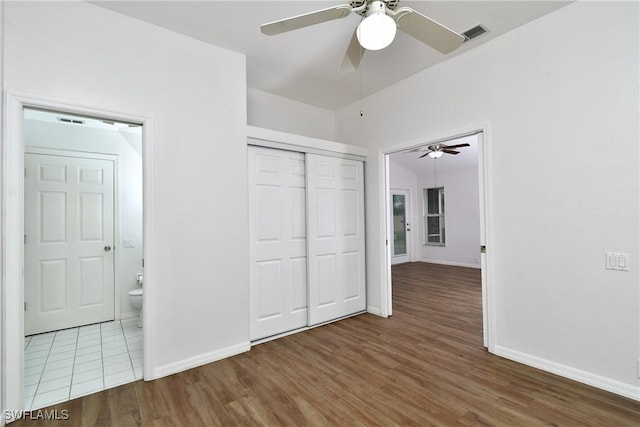 unfurnished bedroom with wood-type flooring, a closet, ceiling fan, and ensuite bathroom