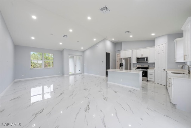 kitchen featuring light countertops, appliances with stainless steel finishes, open floor plan, white cabinetry, and a kitchen island