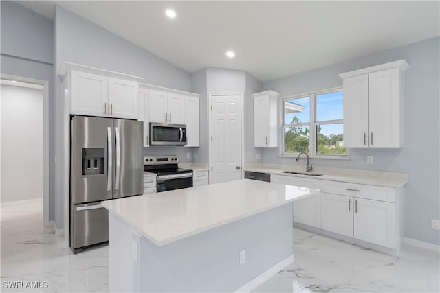 kitchen featuring appliances with stainless steel finishes, vaulted ceiling, sink, white cabinets, and a kitchen island