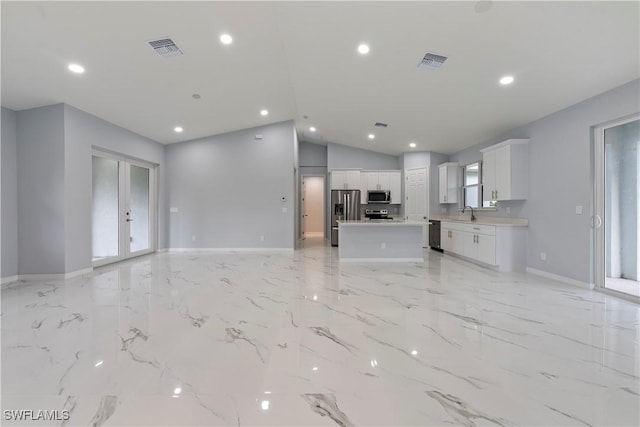 unfurnished living room featuring french doors, vaulted ceiling, and sink