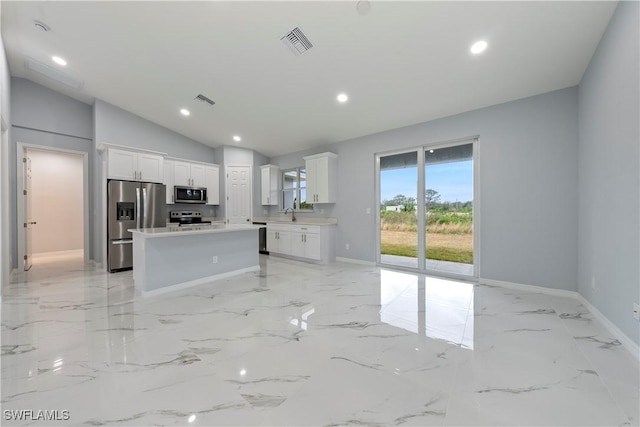 kitchen with appliances with stainless steel finishes, a center island, white cabinetry, and vaulted ceiling