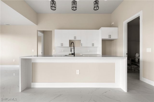 kitchen featuring white cabinetry, sink, and an island with sink