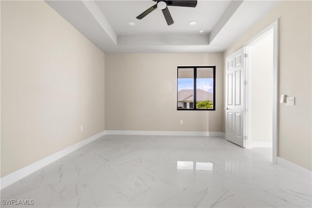 empty room featuring a raised ceiling and ceiling fan