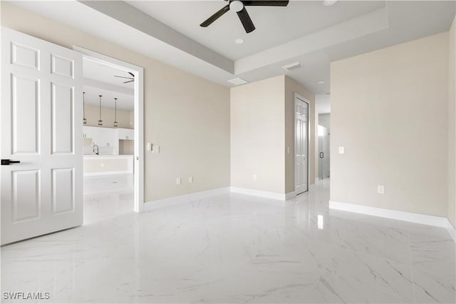 empty room with a raised ceiling and ceiling fan