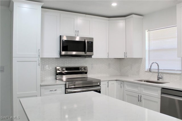 kitchen featuring decorative backsplash, sink, white cabinetry, and stainless steel appliances