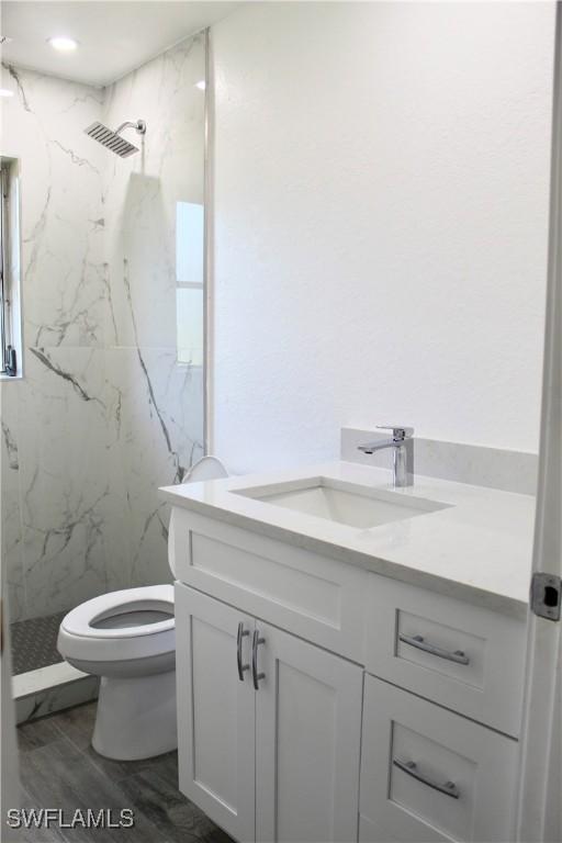 bathroom with vanity, toilet, and a tile shower