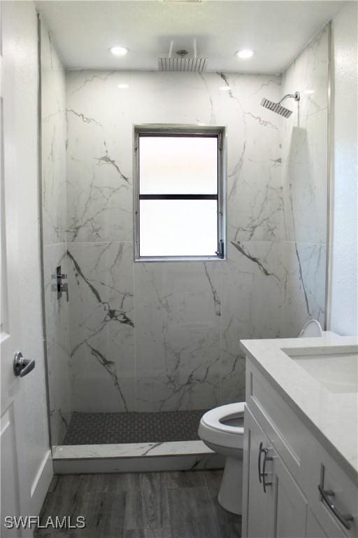 bathroom with vanity, toilet, and tiled shower