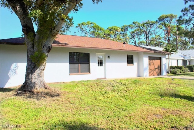 rear view of property featuring a garage and a lawn