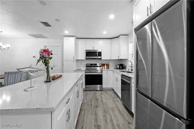 kitchen with stainless steel appliances, white cabinetry, a sink, and backsplash