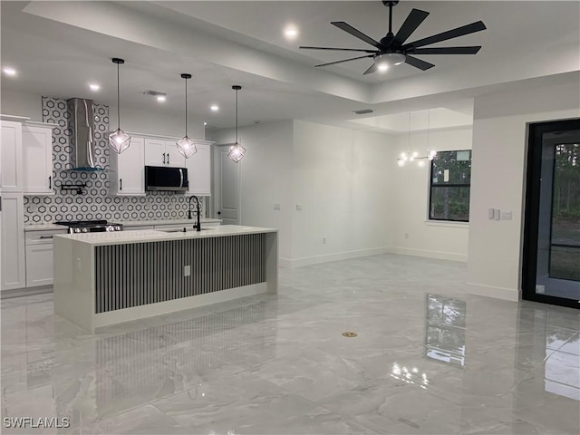 kitchen featuring white cabinetry, an island with sink, and pendant lighting