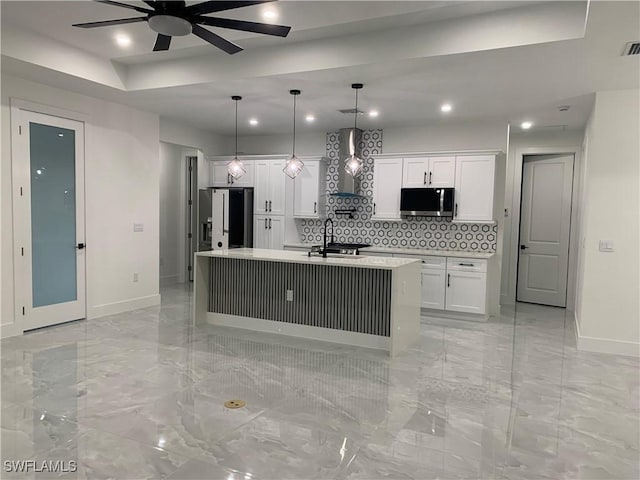 kitchen with appliances with stainless steel finishes, white cabinetry, hanging light fixtures, and an island with sink