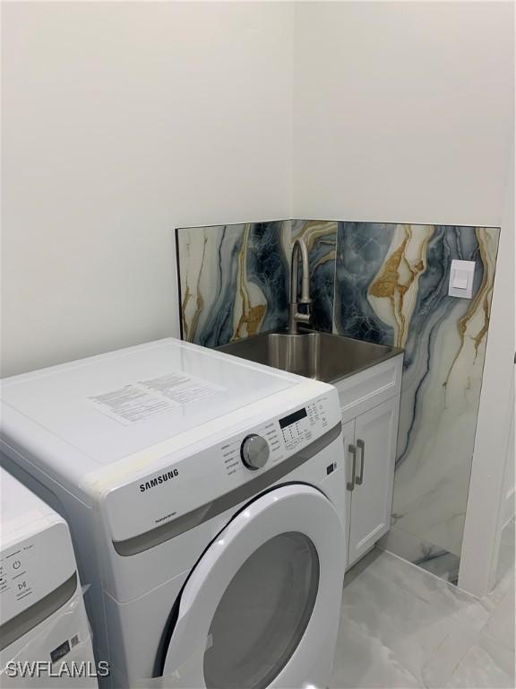 laundry area with washer and clothes dryer, cabinets, and sink